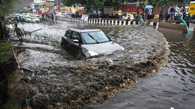 A car makes its way through a waterlogged road after heavy rainfall at Rohtak Road in New Delhi. Public Works Department (PWD) control room reported more than 60 water logging calls from across the city since morning. (Sanchit Khanna / HT Photo) 