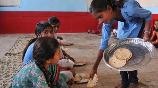 School kids eating chapati and daal with salt which were served to them during interval as mid-day meal(Hindustan Times via Getty Images)