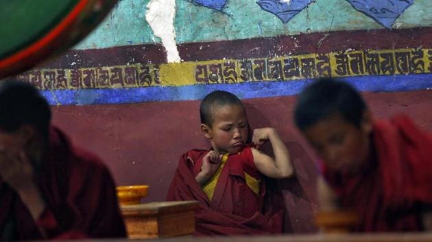 A young Buddhist monk flexes his muscles during morning prayers at Thikse Monastery, Ladakh, 2014 (REUTERS)