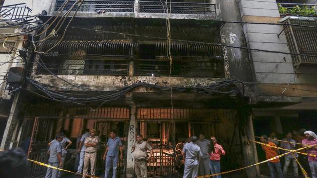 People look at the charred remains of a building where a massive fire broke out, at Zakir Nagar area, in New Delhi, Tuesday, Aug 6, 2019.(PTI)
