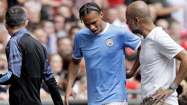 Manchester City's Leroy Sane, left, grimaces walking by Manchester City's manager Pep Guardiola.(AP)