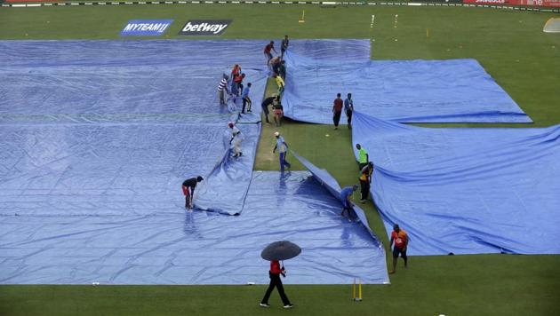 Grounds keepers pull tarpaulins to cover the pitch during the first One-Day International cricket match between India and the West Indies in Providence, Guyana.(AP)