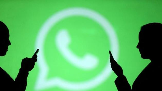 Silhouettes of mobile users are seen next to a screen projection of WhatsApp logo in this picture illustration.(Reuters Photo)
