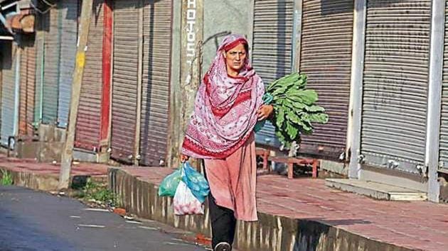 A woman carrying eatables walks past closed shops during restrictions after the government scrapped special status for Kashmir, in Srinagar.(Reuters)