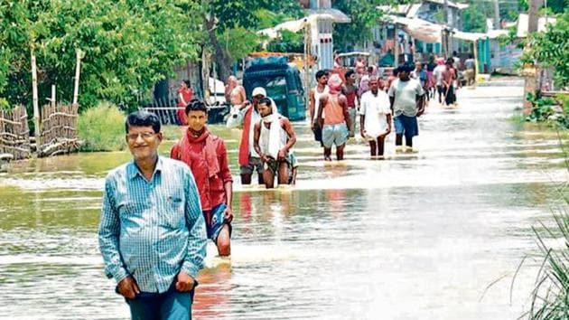 People cross a flooded street following incessant monsoon rainfall, at Aurai Block, of Muzaffarpur district in Bihar.(Lokesh Bihari / Hindustan Times)