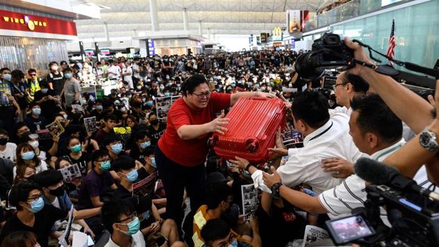 A tourist (C) gives her luggage to security guards as she tries to enter the departures gate during another demonstration by pro-democracy protesters at Hong Kong's international airport. On Tuesday state media upped the ante, calling protesters “mobsters”, warning they must never be appeased and raising the spectre of mainland security forces intervening to quash them. The official state news agency Xinhua warned in a commentary Tuesday that “violent radicals” were pushing Hong Kong into an “abyss”. (Philip FONG / AFP) A tourist (C) gives her luggage to security guards as she tries to enter the departures gate during another demonstration by pro-democracy protesters at Hong Kong's international airport. On Tuesday state media upped the ante, calling protesters “mobsters”, warning they must never be appeased and raising the spectre of mainland security forces intervening to quash them. The official state news agency Xinhua warned in a commentary Tuesday that “violent radicals” were pushing Hong Kong into an “abyss”. (Philip FONG / AFP)