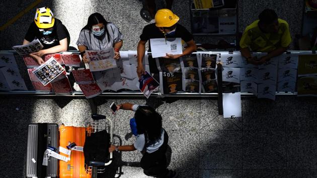 Protesters wear helmets as they deliver leaflets to arriving travellers. India has issued a travel advisory to its citizens travelling to Hong Kong. “Indian passengers are advised to be in touch with airlines to find alternative travel routes to avoid inconvenience, till normalcy is restored in airport operations,” the notice read. (Philip FONG / AFP) Protesters wear helmets as they deliver leaflets to arriving travellers. India has issued a travel advisory to its citizens travelling to Hong Kong. “Indian passengers are advised to be in touch with airlines to find alternative travel routes to avoid inconvenience, till normalcy is restored in airport operations,” the notice read. (Philip FONG / AFP)