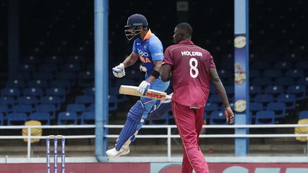 India's captain Virat Kohli celebrating his century as West Indies bowler captain Jason Holder looks on during their second One-Day International.(AP)