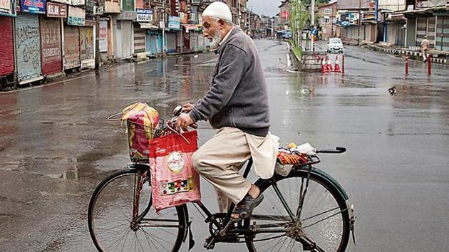 A Kashmiri man rides a bicycle through a deserted street during security lockdown in Srinagar. (Photo PTI)