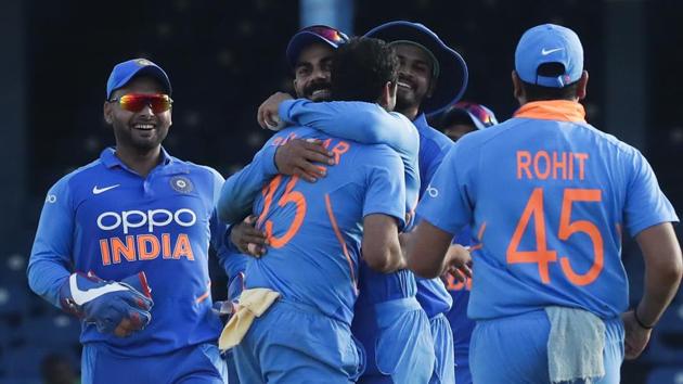 India bowler Bhuvneshwar Kumar, center, is hugged by captain Virat Kohli after catching and bowling out West Indies batsman Roston Chase.(AP)