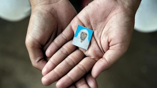 Irshad Khan, 24, holds a picture of his late father Pehlu, 55, in Jaisinghpur. The 92-page judgment, which highlights the glaring holes in the investigative process and the prosecution’s case, was delivered by additional district judge Sarita Swami.(Reuters)