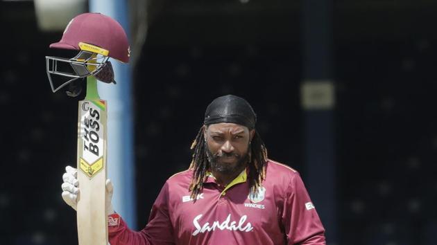 West Indies opener Chris Gayle raises his bat to the crowd after reaching a half century during the third One-Day International cricket match India in Port of Spain.(AP)