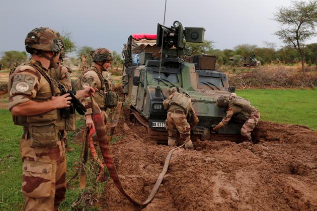 Soldiers try to move an armoured vehicle from the mud in the Gourma region. One unit wanted to check a forest where weapons had been abandoned, but the troops were still stuck towing vehicles. The next morning a joint Malian-French mission visited a Fulani village next to woodland where they had spotted some men fleeing. The village chief, a bearded man with a green scarf and sky-blue robe, denied seeing any armed men. (Benoit Tessier / REUTERS)