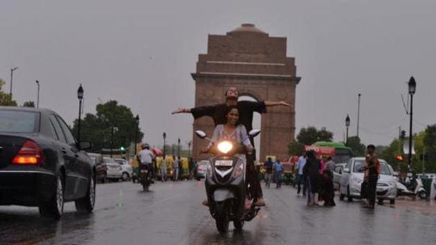 Girls enjoy the rain, at Rajpath in New Delhi on Monday. (ANI Photo)