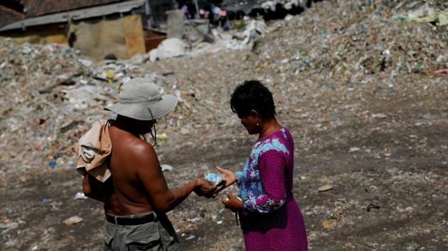 Sunarni receives money from a scavenger after they unload rubbish at Bangun village. Masud said the money from sorting trash is used to fund activities such as sending villagers on the Haj pilgrimage to Islam’s holiest sites in Saudi Arabia. Every year 17-20 people from this village go on a Haj. That’s funded from this waste. (Willy Kurniawan / REUTERS) Sunarni receives money from a scavenger after they unload rubbish at Bangun village. Masud said the money from sorting trash is used to fund activities such as sending villagers on the Haj pilgrimage to Islam’s holiest sites in Saudi Arabia. Every year 17-20 people from this village go on a Haj. That’s funded from this waste. (Willy Kurniawan / REUTERS)