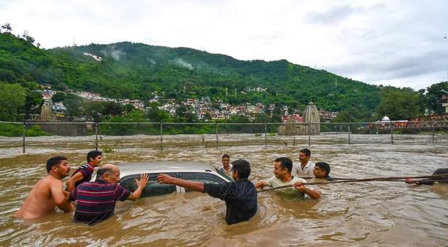 People push a submerged car in the flood waters of the Beas river in Mandi, Himachal Pradesh on Sunday.(Photo: Birbal Sharma /HT PHOTO.)