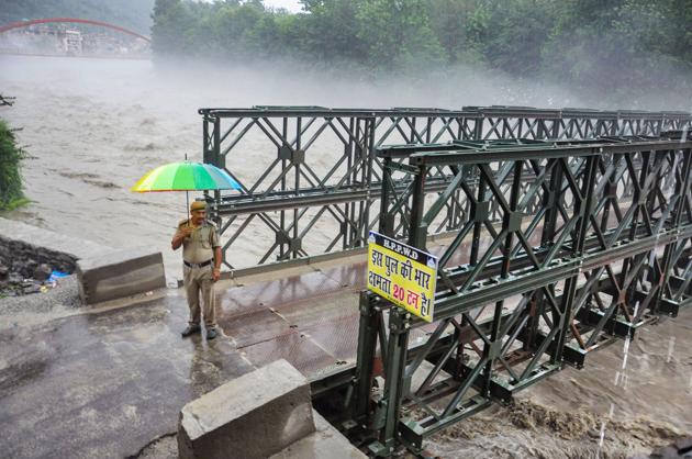 Kullu: A policeman stands at the entry point of the bypass road bridge that was closed for the vehicular traffic as Beas river was flowing above the danger mark, in Kullu.(PTI)