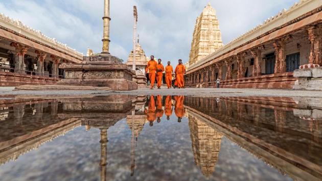 Members of Virupaksha Temple and Hindu devotees walk in the temple's premises, as their reflections are seen in a puddle of water in Hampi, Karnataka. Hampi, UNESCO's World Heritage site, was till recently under the threat of floods from the overflowing Tungabhadra river. (AFP) Members of Virupaksha Temple and Hindu devotees walk in the temple's premises, as their reflections are seen in a puddle of water in Hampi, Karnataka. Hampi, UNESCO's World Heritage site, was till recently under the threat of floods from the overflowing Tungabhadra river. (AFP)
