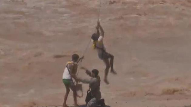 The personnel lands on the small strip of concrete and makes his way to the stranded men. (Photo: ANI/screengrab) The personnel lands on the small strip of concrete and makes his way to the stranded men. (Photo: ANI/screengrab)