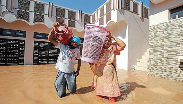 Residents of Motipur Khalsa village carrying their household items on Monday to a safer place after their houses were flooded,(Pardeep Pandit/HT)