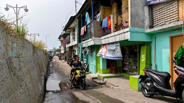 Two men ride a motorcycle as water from the sea leaks through the giant sea wall. Built in an earthquake zone, on swamplands, near the confluence of 13 rivers, the city’s foundations have been further stressed by unchecked development, heavy traffic, and poor urban planning. Flooding is common during the tropical nation’s wet season and that is expected get worse as sea levels rise due to global warming. (BAY ISMOYO / AFP) Two men ride a motorcycle as water from the sea leaks through the giant sea wall. Built in an earthquake zone, on swamplands, near the confluence of 13 rivers, the city’s foundations have been further stressed by unchecked development, heavy traffic, and poor urban planning. Flooding is common during the tropical nation’s wet season and that is expected get worse as sea levels rise due to global warming. (BAY ISMOYO / AFP)
