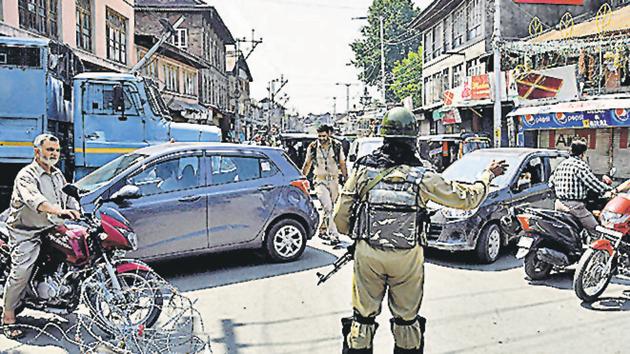 CRPF personnel stops vehicles near a temporary barricade set up by police during restriction in downtown area of Srinagar on Friday. (ANI photo)