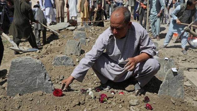 An Afghan man put flowers on a grave of his relative during a mass funeral after a suicide bomb blast at a wedding in Kabul, Afghanistan . (Reuters Photo) An Afghan man put flowers on a grave of his relative during a mass funeral after a suicide bomb blast at a wedding in Kabul, Afghanistan . (Reuters Photo)