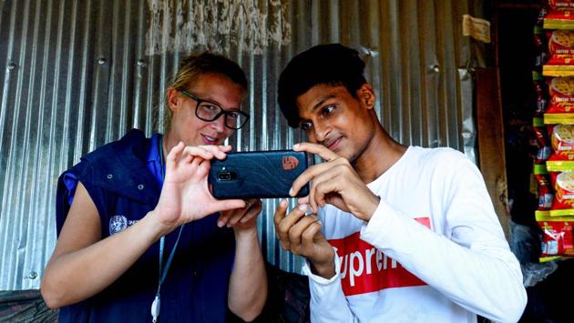 World Food Programme (WFP) official Gemma Snowdon (L) coaches Rohingya youth Mohammad Rafiq on methods to take better photos with his mobile phone at the Kutupalong refugee camp. The 19-year-old budding photographer, who fled to Bangladesh in August 2017 after a military crackdown in Myanmar, uses his mobile phone to record the daily lives of nearly one million stateless Rohingya in a vast camp in southern Bangladesh. (Munir UZ ZAMAN / AFP) World Food Programme (WFP) official Gemma Snowdon (L) coaches Rohingya youth Mohammad Rafiq on methods to take better photos with his mobile phone at the Kutupalong refugee camp. The 19-year-old budding photographer, who fled to Bangladesh in August 2017 after a military crackdown in Myanmar, uses his mobile phone to record the daily lives of nearly one million stateless Rohingya in a vast camp in southern Bangladesh. (Munir UZ ZAMAN / AFP)