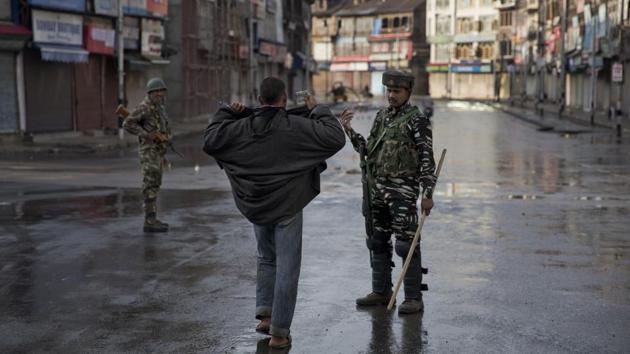 A paramilitary soldier orders a Kashmiri man to lift his robe before frisking him during curfew. Weeks later, police in riot gear are there to help a limited stream of vehicles and pedestrians navigate the security maze. (Dar Yasin / AP) A paramilitary soldier orders a Kashmiri man to lift his robe before frisking him during curfew. Weeks later, police in riot gear are there to help a limited stream of vehicles and pedestrians navigate the security maze. (Dar Yasin / AP)