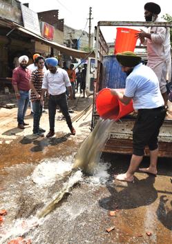 Youth Akali Dal workers throwing sewage from Buddha Nullah outside Congress MLA Rakesh Pandey’s office in Ludhiana on Friday.(Gurpreet Singh/HT)