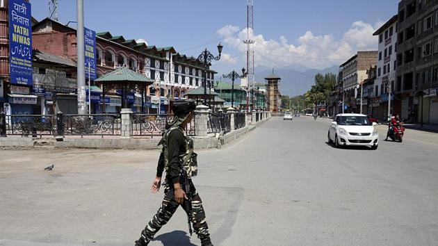 CRPF personnel stand guard in front of closed shops in Srinagar.(ANI)