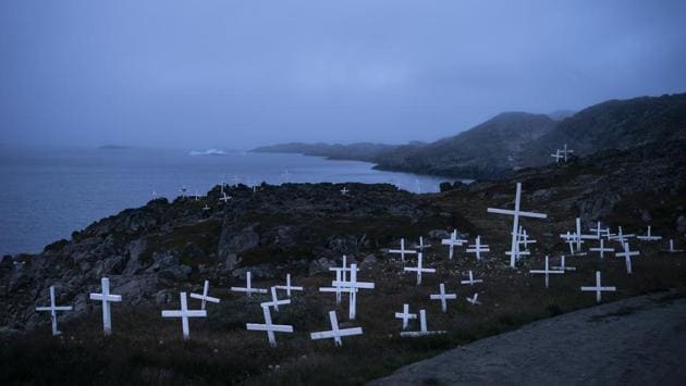Crosses stand in a cemetery as an iceberg floats in the distance during a foggy morning in Kulusuk. Willis, a NASA scientist, estimates that by the year 2100, Greenland alone could cause 3 or 4 feet (more than 1 meter) of sea level rise. (Felipe Dana / AP) Crosses stand in a cemetery as an iceberg floats in the distance during a foggy morning in Kulusuk. Willis, a NASA scientist, estimates that by the year 2100, Greenland alone could cause 3 or 4 feet (more than 1 meter) of sea level rise. (Felipe Dana / AP)