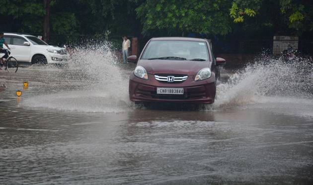 Vehicles negotiate a waterlogged roundabout in Sector 10, Panchkula, on Saturday.(Sant Arora/HT)