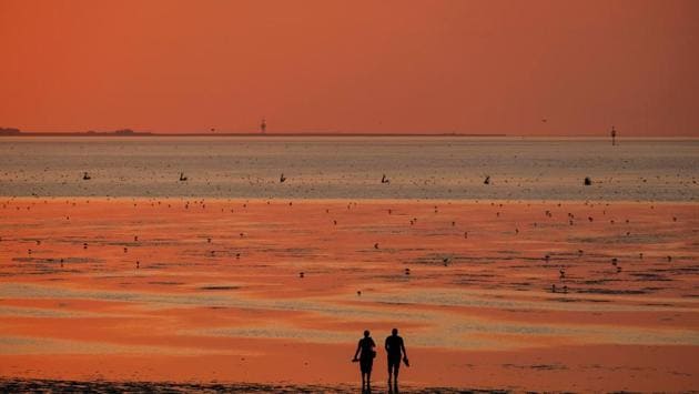 The sun sets behind people walking on a North Sea beach in Cuxhaven, northern Germany. (Patrik Stollarz / AFP) The sun sets behind people walking on a North Sea beach in Cuxhaven, northern Germany. (Patrik Stollarz / AFP)