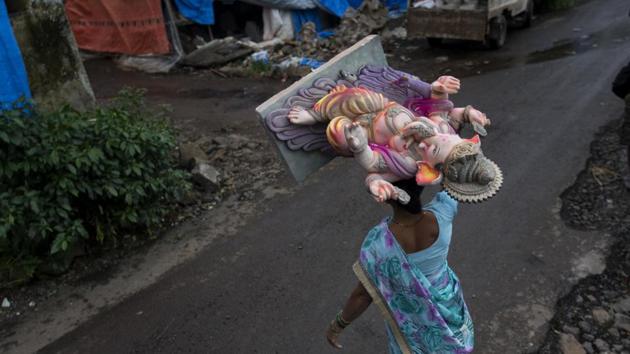 A woman carries a large, still wet idol of Ganesha atop her head to dry at Hamrapur village. Many workshops have seen the participation of family members, including the women of the household, who may not routinely have been involved in the work as the September 2 advent of the ten-day festival draws closer. (Satish Bate / HT Photo) A woman carries a large, still wet idol of Ganesha atop her head to dry at Hamrapur village. Many workshops have seen the participation of family members, including the women of the household, who may not routinely have been involved in the work as the September 2 advent of the ten-day festival draws closer. (Satish Bate / HT Photo)
