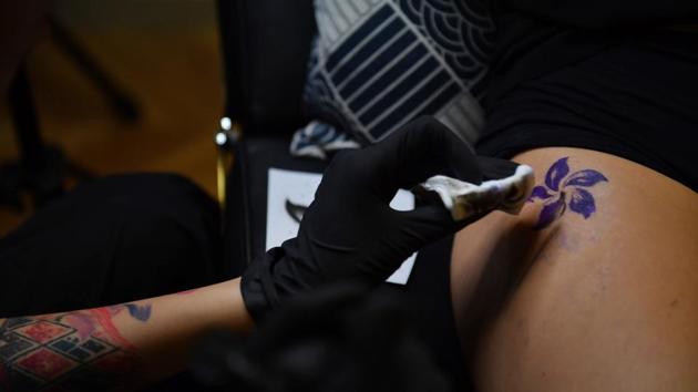 As a tattooist’s black ink fills the petals of Hong Kong’s Bauhinia flower on her upper thigh, ‘C’ says the indelible act of rebellion will forever serve as a reminder of the city’s summer of defiance. “No matter how many years pass, I’ll remember this year; I decided to stand up to fight for my freedom and to fight for what I really care about,” said the finance worker who asked to be identified only by an initial. (Lillian Suwanrumpha / AFP) As a tattooist’s black ink fills the petals of Hong Kong’s Bauhinia flower on her upper thigh, ‘C’ says the indelible act of rebellion will forever serve as a reminder of the city’s summer of defiance. “No matter how many years pass, I’ll remember this year; I decided to stand up to fight for my freedom and to fight for what I really care about,” said the finance worker who asked to be identified only by an initial. (Lillian Suwanrumpha / AFP)