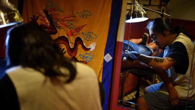 Tattoo artist Vincent Yau works on a ‘Hong Kong/Add Oil’ calligraphy tattoo on first time client ‘Jerry’ at Mofo Tattoo studio. Since June when the largest protests to hit Hong Kong in decades erupted, tattoo studios have received a surge in requests for protest-related artworks. (Lillian Suwanrumpha / AFP) Tattoo artist Vincent Yau works on a ‘Hong Kong/Add Oil’ calligraphy tattoo on first time client ‘Jerry’ at Mofo Tattoo studio. Since June when the largest protests to hit Hong Kong in decades erupted, tattoo studios have received a surge in requests for protest-related artworks. (Lillian Suwanrumpha / AFP)