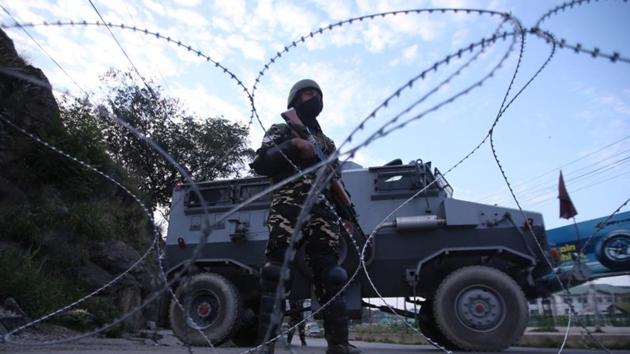 A security personnel stands guard on a deserted road in Srinagar.(Reuters image)