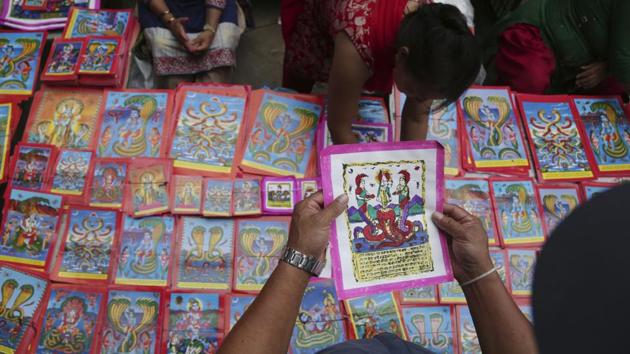 A Nepalese man checks a traditional painting among machine printed posters for sale at a market during Naag Panchami festival. Tej Kumari said machine printed ones have gained popularity, leading to a drastic reduction in the number of customers. (Niranjan Shrestha / AP) A Nepalese man checks a traditional painting among machine printed posters for sale at a market during Naag Panchami festival. Tej Kumari said machine printed ones have gained popularity, leading to a drastic reduction in the number of customers. (Niranjan Shrestha / AP)