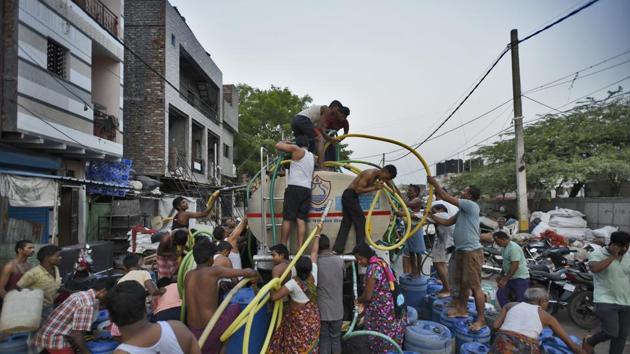 People fill their empty containers with water using lengths of hose pipe from a Delhi Jal Board tanker, at Sanjay Colony in Okhla Phase II.(Burhaan Kinu/HT FILE PHOTO)