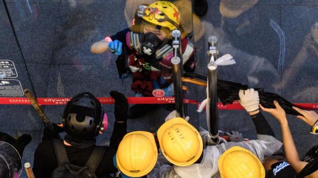 A medic tries to communicate with protesters behind the blocked doors of a shopping mall, shortly after protesters told others to leave following the arrival of police water cannon during a protest in Tsuen Wan. Like Abby and Nick, many are young, bookish and should be on the fast-track to well-paying jobs in the city’s financial services sector. Instead a political awakening has thrust them onto the frontlines. (Anthony Wallace / AFP) A medic tries to communicate with protesters behind the blocked doors of a shopping mall, shortly after protesters told others to leave following the arrival of police water cannon during a protest in Tsuen Wan. Like Abby and Nick, many are young, bookish and should be on the fast-track to well-paying jobs in the city’s financial services sector. Instead a political awakening has thrust them onto the frontlines. (Anthony Wallace / AFP)