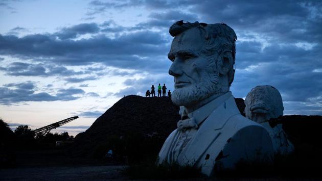 Busts of former US Presidents Abraham Lincoln and George Washington can be seen as people get an overview from a mountain of mulch while they tour the decaying remains of salvaged busts of former US Presidents, in Williamsburg, Virginia. Howard Hankins rescued the giant busts from the closed Presidents Park in Colonial Williamsburg when he was commissioned to destroy them. (Brendan Smialowski / AFP) Busts of former US Presidents Abraham Lincoln and George Washington can be seen as people get an overview from a mountain of mulch while they tour the decaying remains of salvaged busts of former US Presidents, in Williamsburg, Virginia. Howard Hankins rescued the giant busts from the closed Presidents Park in Colonial Williamsburg when he was commissioned to destroy them. (Brendan Smialowski / AFP)