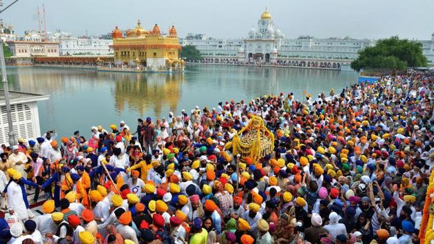 Sikh devotees carry Sri Guru Granth Sahib Ji, the holy book of the Sikhs, in a golden palanquin at the Golden Temple during a religious procession on the occasion of the 415th installation anniversary of Sri Guru Granth Sahib, in Amritsar, Punjab. (PTI) 