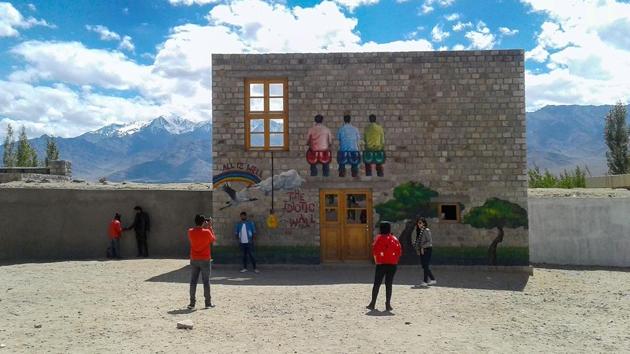 Tourists pose for pictures at a duplicate 'Rancho's Wall' on the premises of Druk Padma Karpo School at Shey in Leh district of Ladakh. (PTI) 