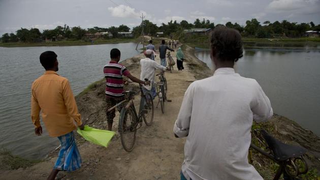 Villagers walk on an embankment on their way to check names in the final list of the National Register of Citizens (NRC) at an NRC center in Pabhokati village in Morigaon district, in the northeastern Indian state of Assam. (AP) Villagers walk on an embankment on their way to check names in the final list of the National Register of Citizens (NRC) at an NRC center in Pabhokati village in Morigaon district, in the northeastern Indian state of Assam. (AP)