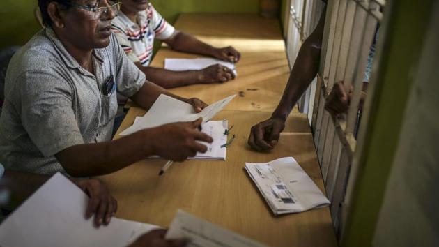 Officials check a man's name on the National Register of Citizens (NRC) at a government office in Guwahati, Assam.(Bloomberg)