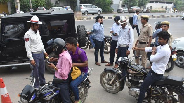 Traffic police personnel issue challans to those violating traffic rules at Maharana Pratap Chowk, in Gurugram.(Yogesh Kumar/Hindustan Times)