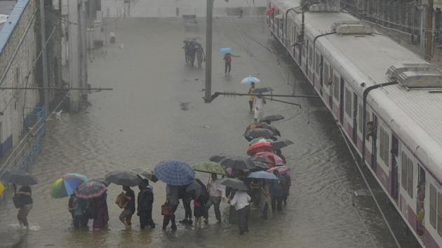 People walk on the railway track as trains stop working due to water logging on the railway track at Matunga (West) railway station in Mumbai on Wednesday.(Vijayanand Gupta/HT Photo)