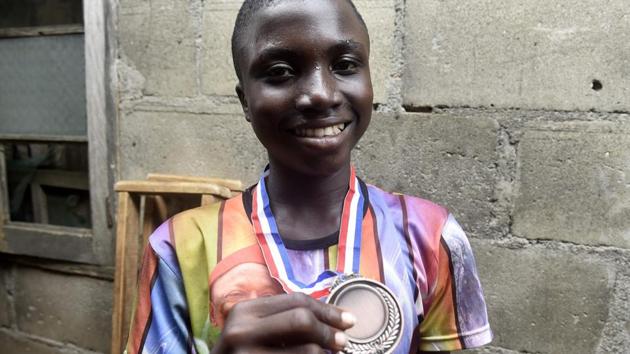 Fourteen-year-old mechanic Jamiu Ninilowo holds a medal he won following a chess tournament. He had to earn money for his family after his mother’s leg was mangled in an accident as she picked scrap at a local refuse site to sell on for a meagre profit. In February, Ninilowo joined the club and is now its best player. After he won a tournament in April, an impressed donor partnered with Chess in Slums to pay for his secondary education. (Pius Utomi Ekpei/ AFP) Fourteen-year-old mechanic Jamiu Ninilowo holds a medal he won following a chess tournament. He had to earn money for his family after his mother’s leg was mangled in an accident as she picked scrap at a local refuse site to sell on for a meagre profit. In February, Ninilowo joined the club and is now its best player. After he won a tournament in April, an impressed donor partnered with Chess in Slums to pay for his secondary education. (Pius Utomi Ekpei/ AFP)