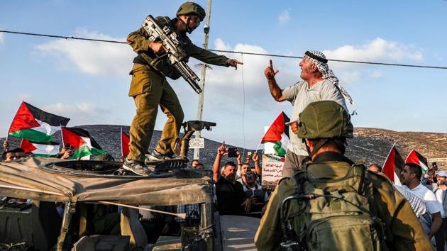 A Palestinian protester yells at an Israeli soldier as he confronts him atop an Israeli army vehicle during a protest against Israeli forces conducting an exercise in a residential area near the Palestinian village of Naqura, northwest of Nablus in the West Bank. (Jaafar Ashtiyeh / AFP) 